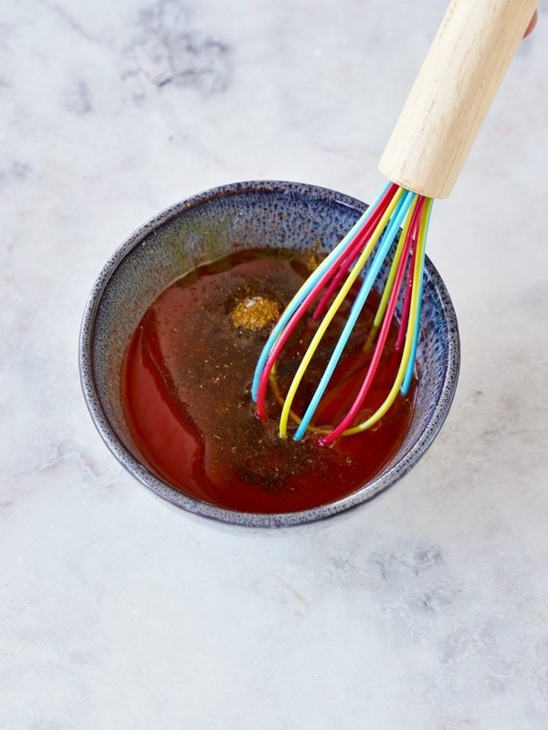 Ras el Hanout tomato dressing in small bowl with whisk