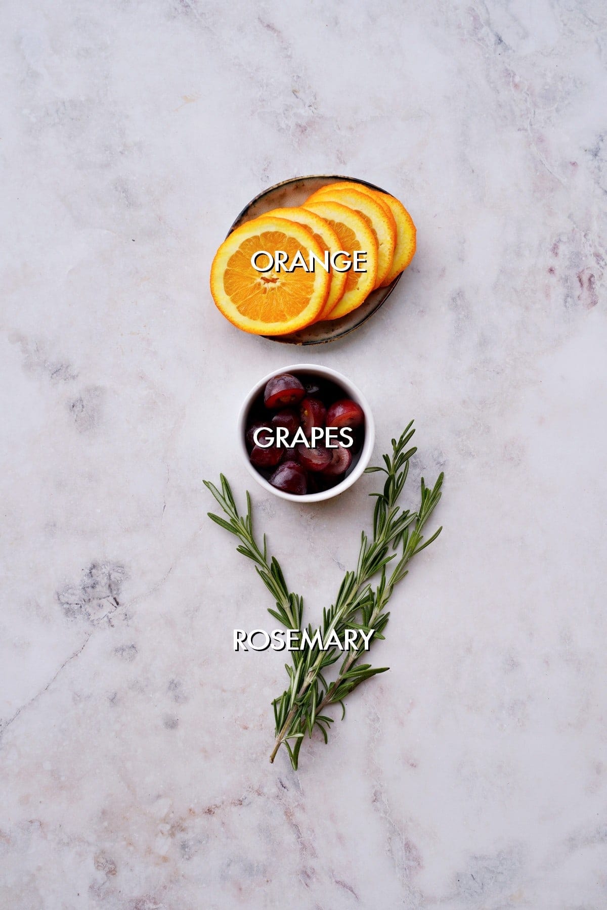 orange, grapes and rosemary on white backdrop