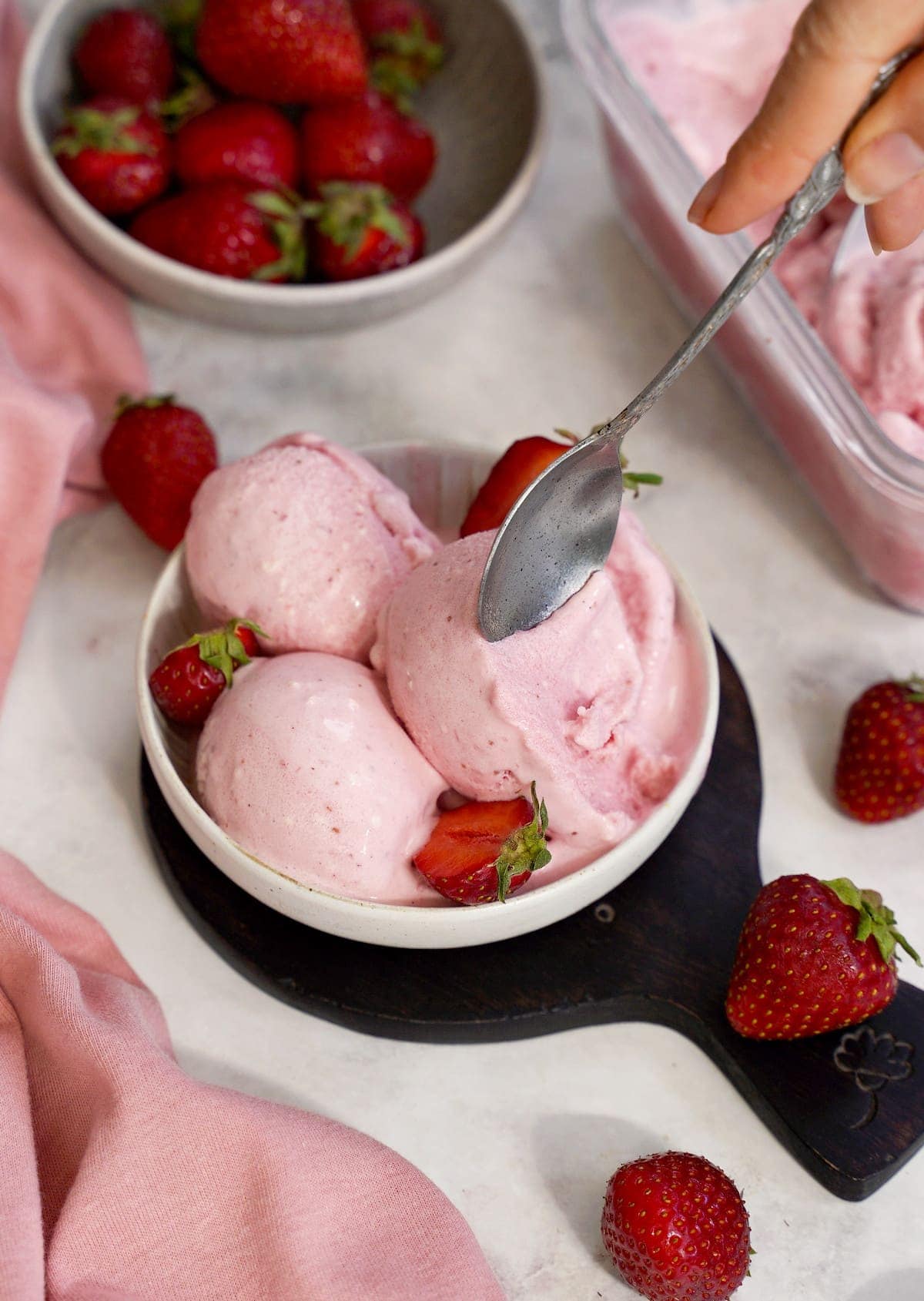 spoon digging into creamy dairy-free ice cream with strawberries