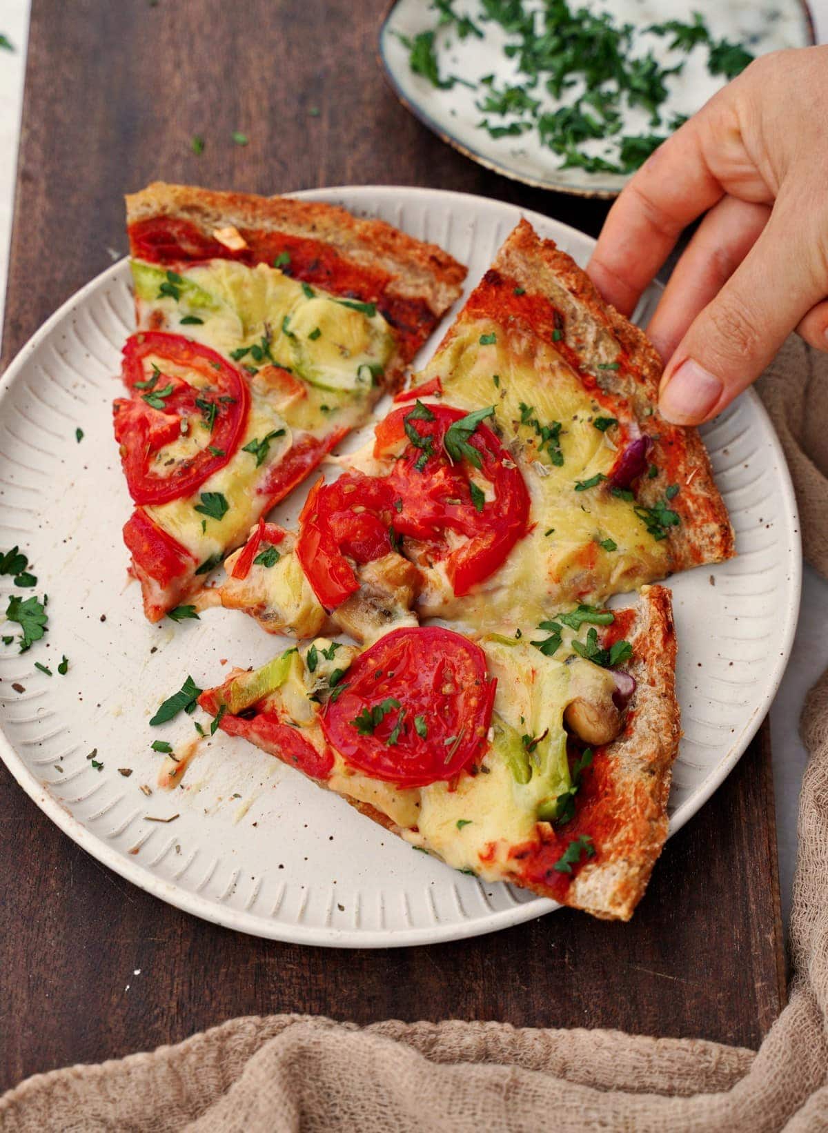 3 vegane Pizzastücke auf einem weißen Teller