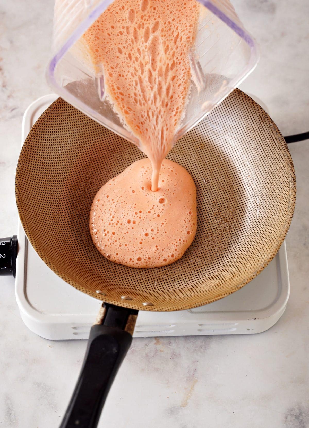 pouring red batter into skillet