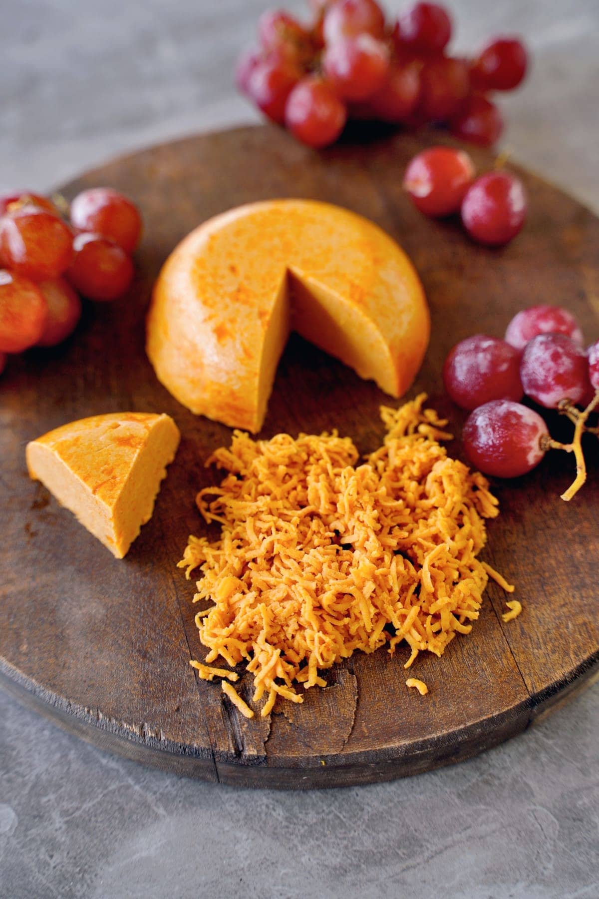 Geriebener veganer Cheddar Käse mit Crackern und Weintrauben