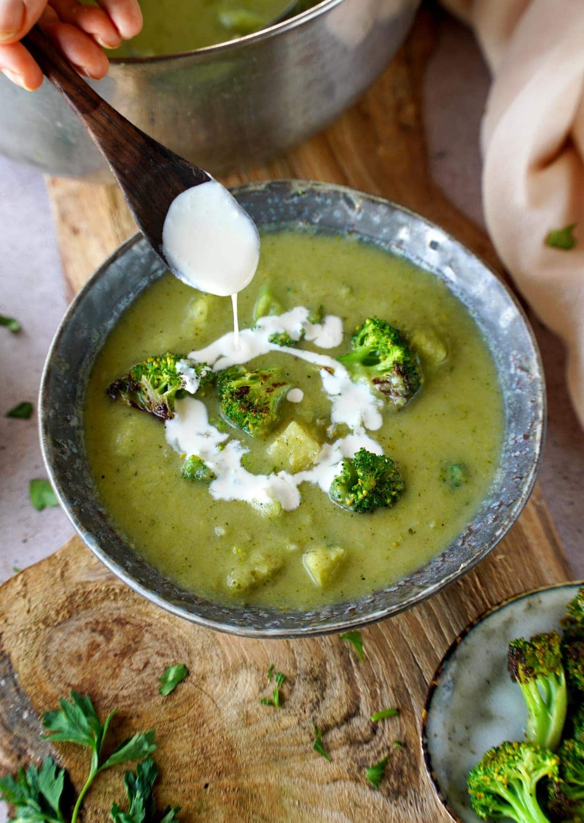 Beträufeln von Brokkoli-Suppe mit veganer Sahne