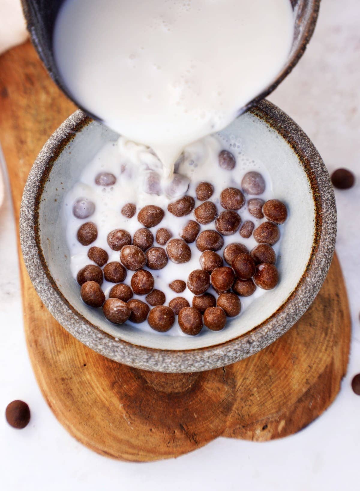 pouring dairy-free milk into bowl with homemade chocolate cereal puffs