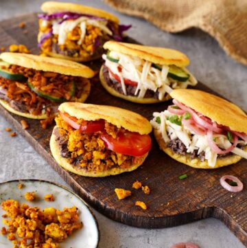 6 arepas on wooden board with healthy fillings
