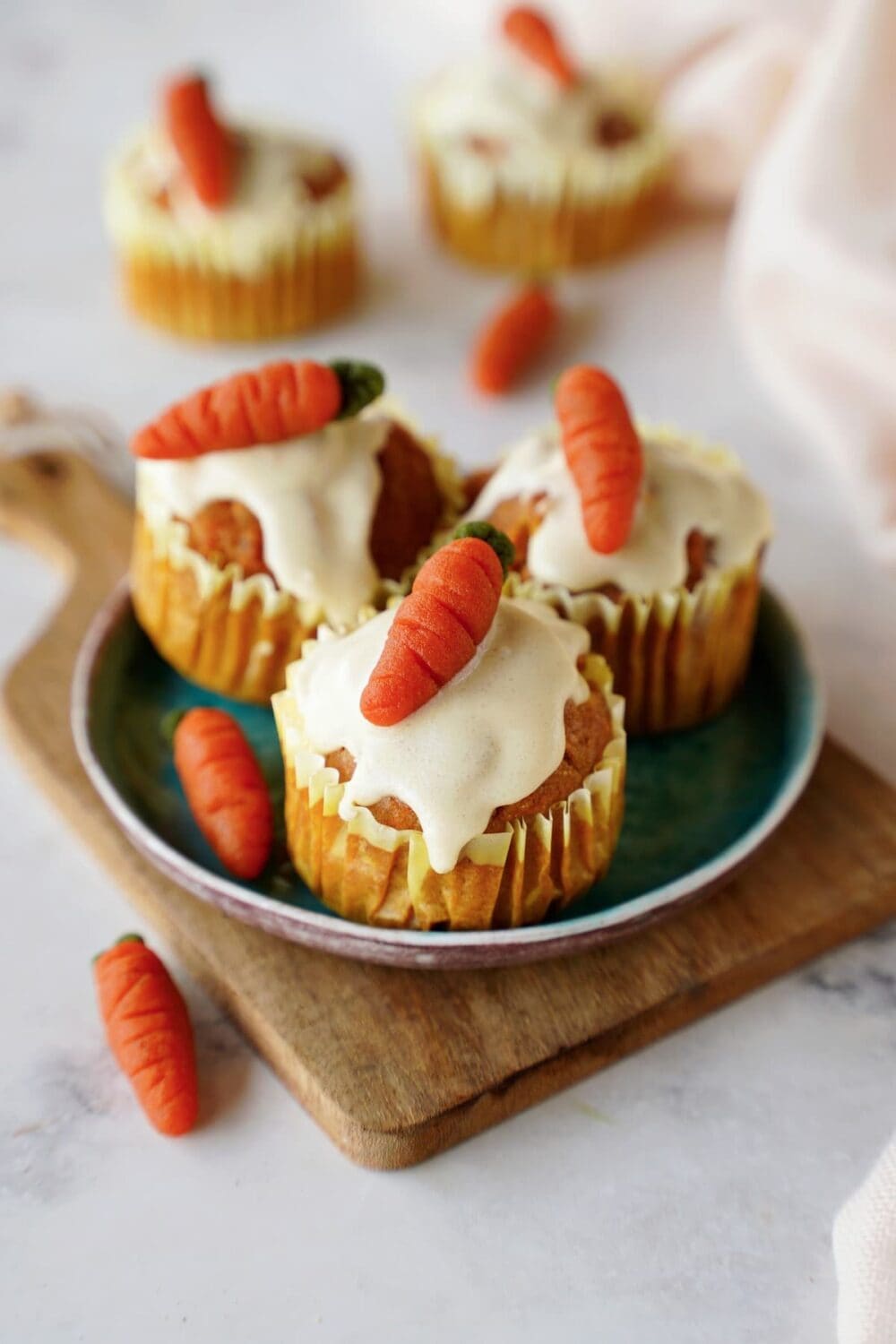 healthy carrot muffins with icing and marzipan carrots on small plate