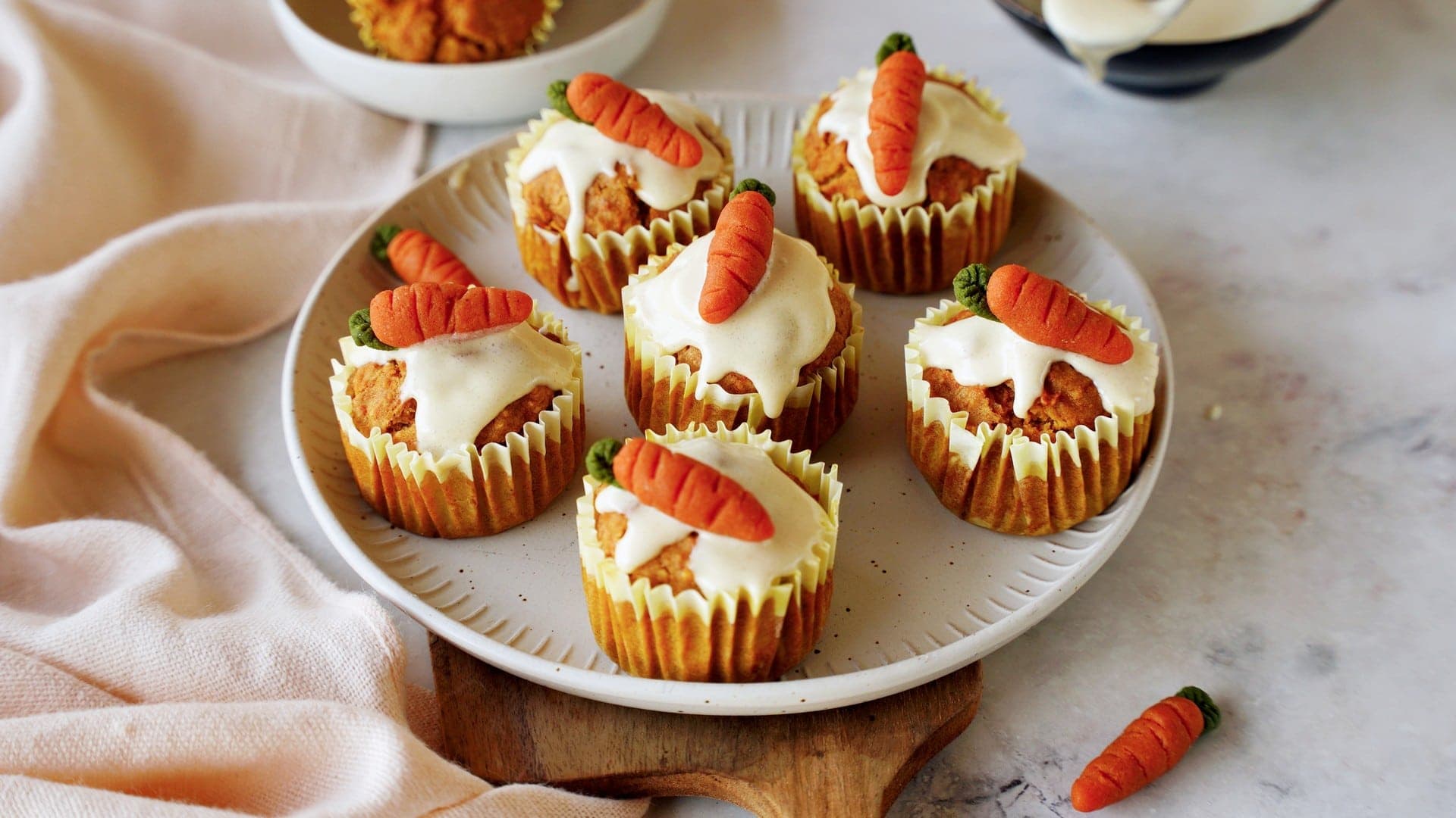 horizontal shot of vegan carrot muffins with sugar-free icing and marzipan carrots