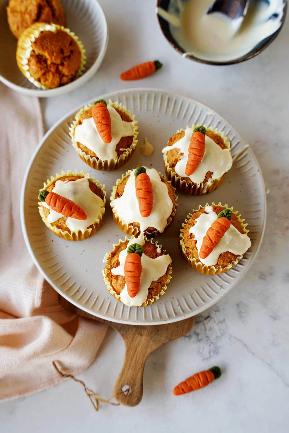 top shot of carrot cake muffins with icing and marzipan carrots