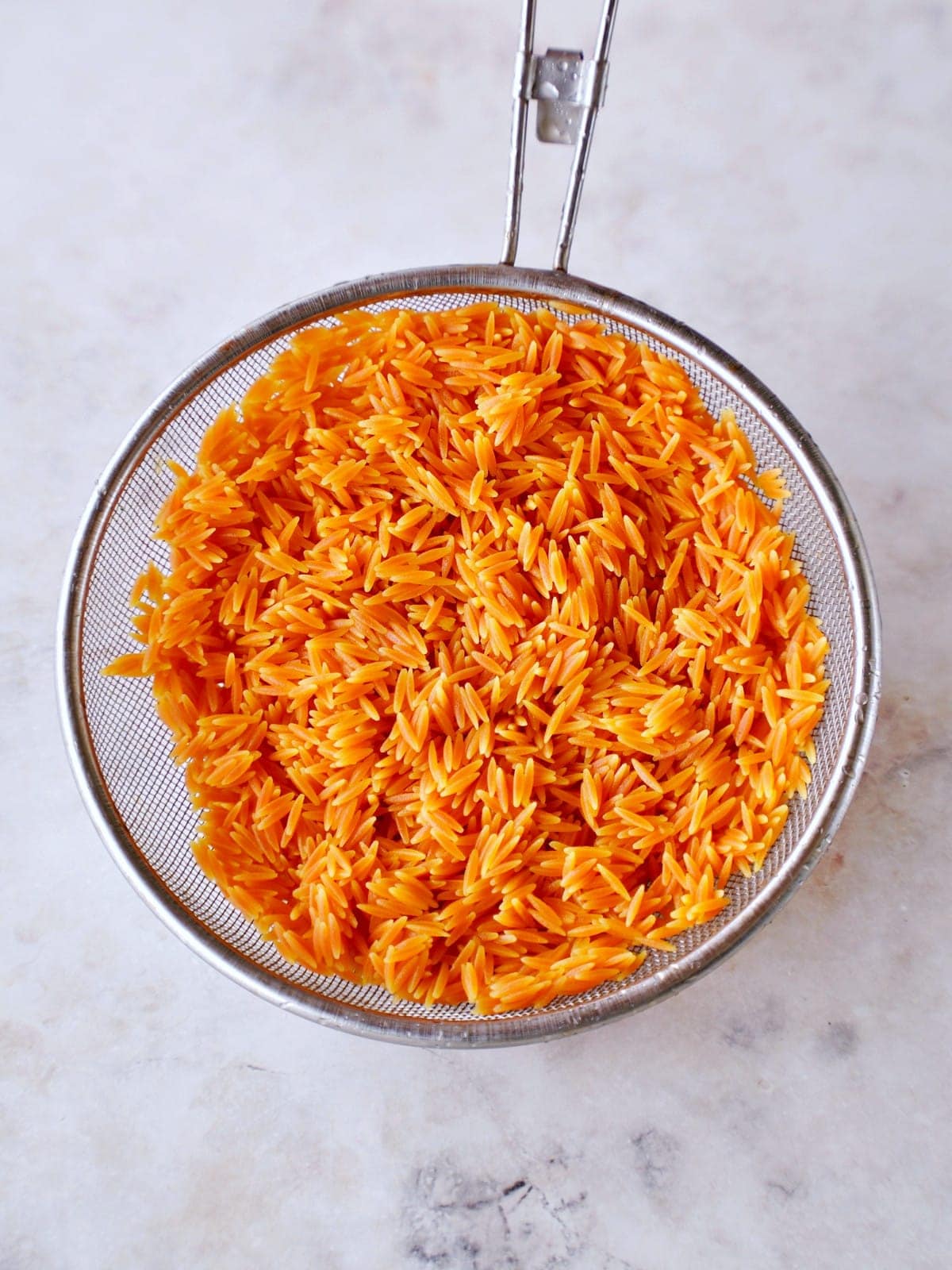 cooked red lentil risoni in sieve