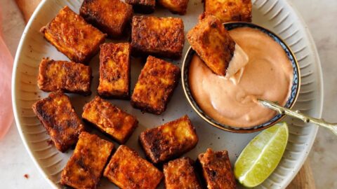 air fried tofu on white plate with creamy dip and lime slices