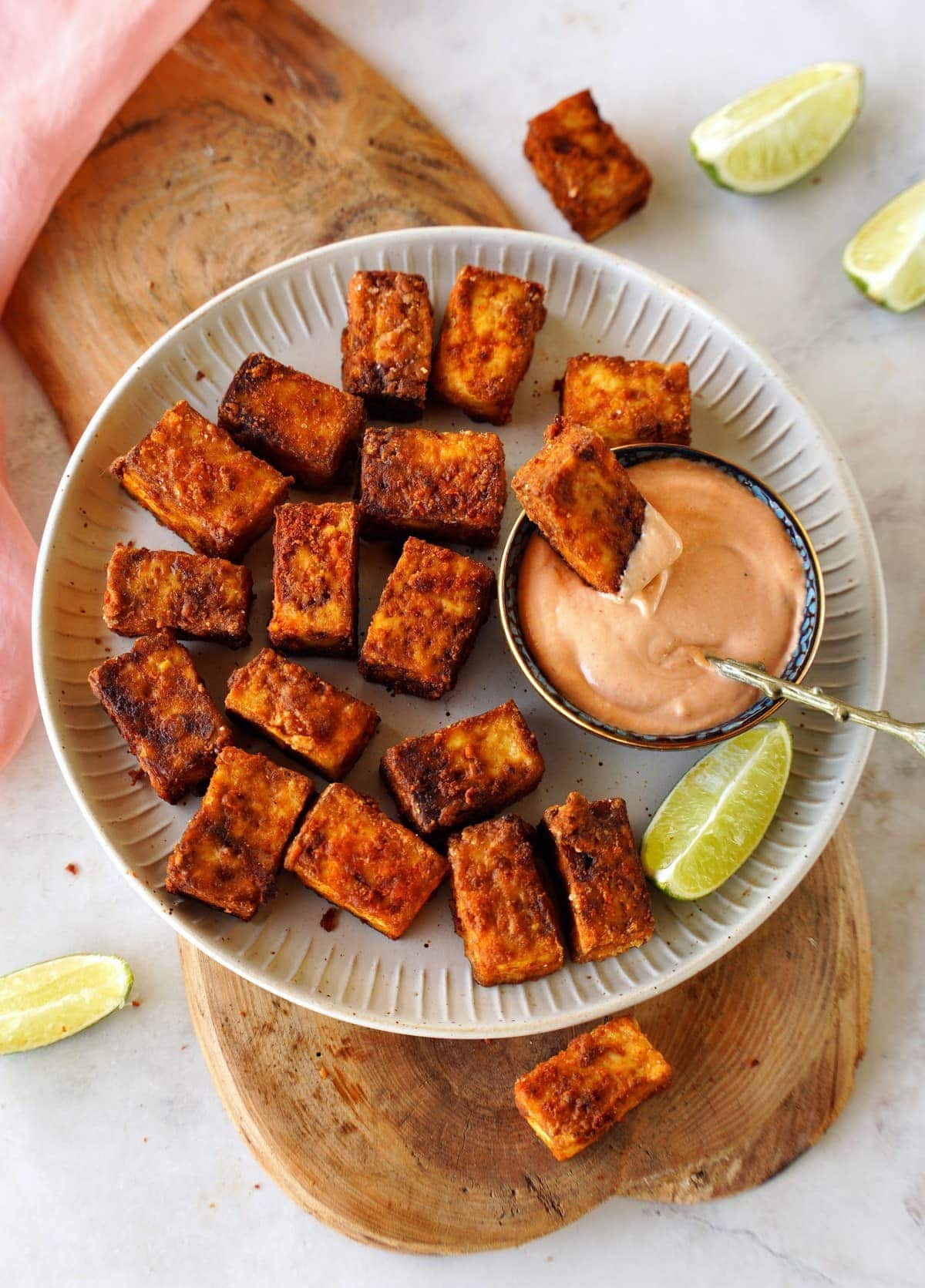 air fried tofu on white plate with creamy dip and lime slices