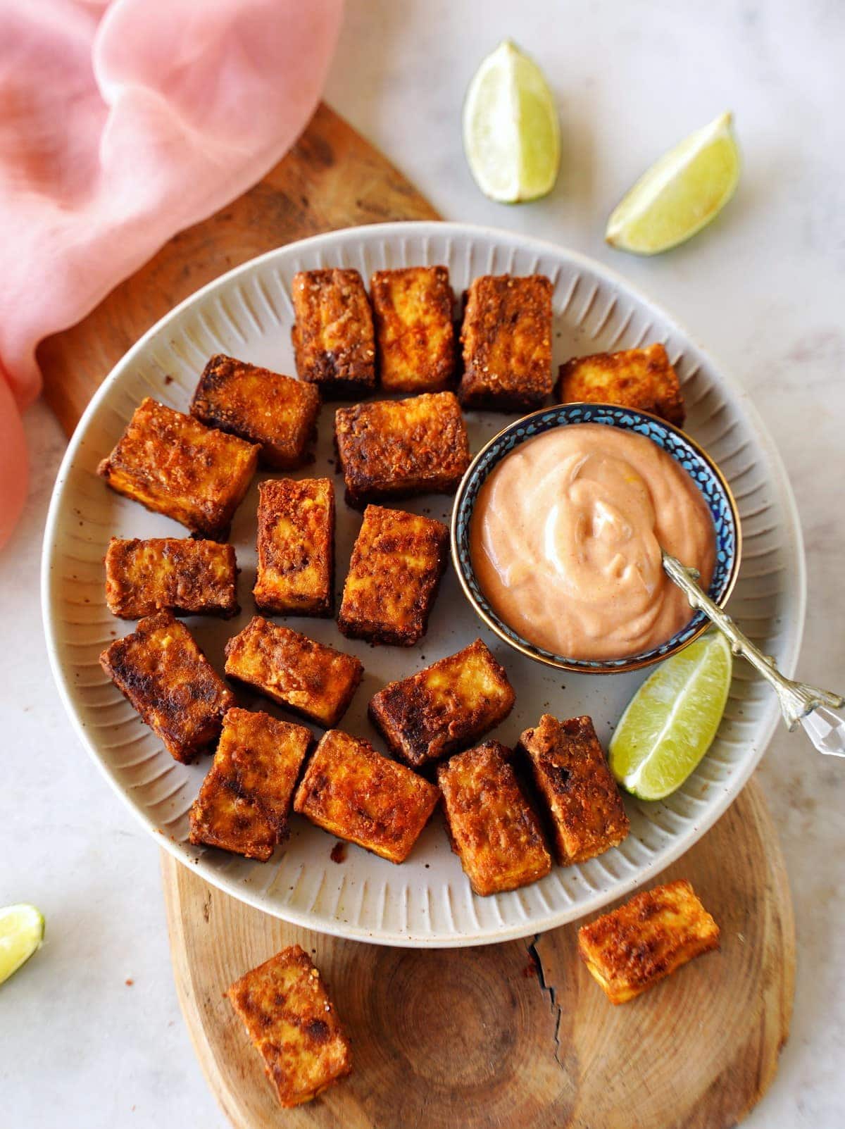 air fryer tofu on white plate with creamy dip and lime slices