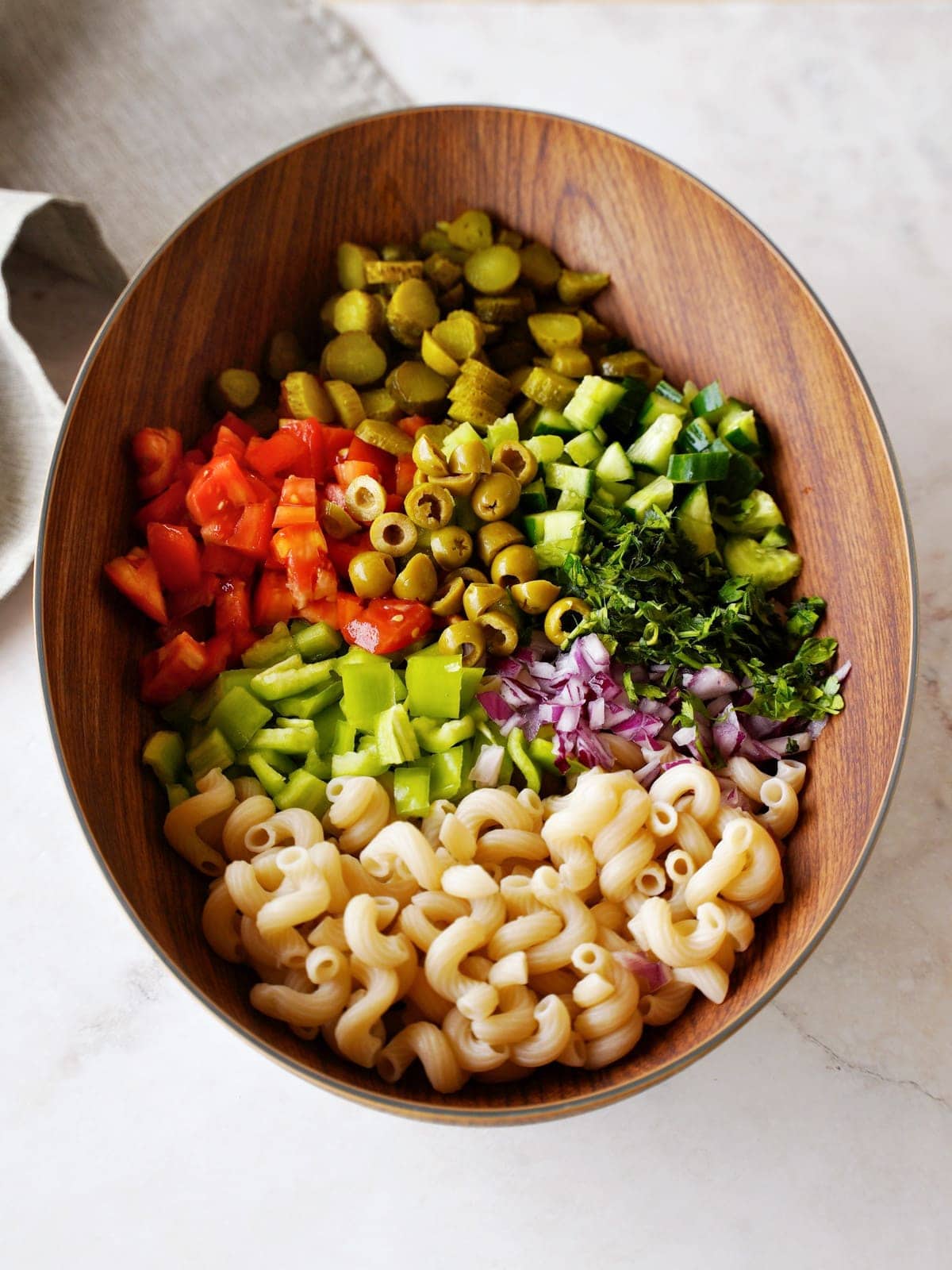 chopped vegetables and cooked pasta in large wooden bowl