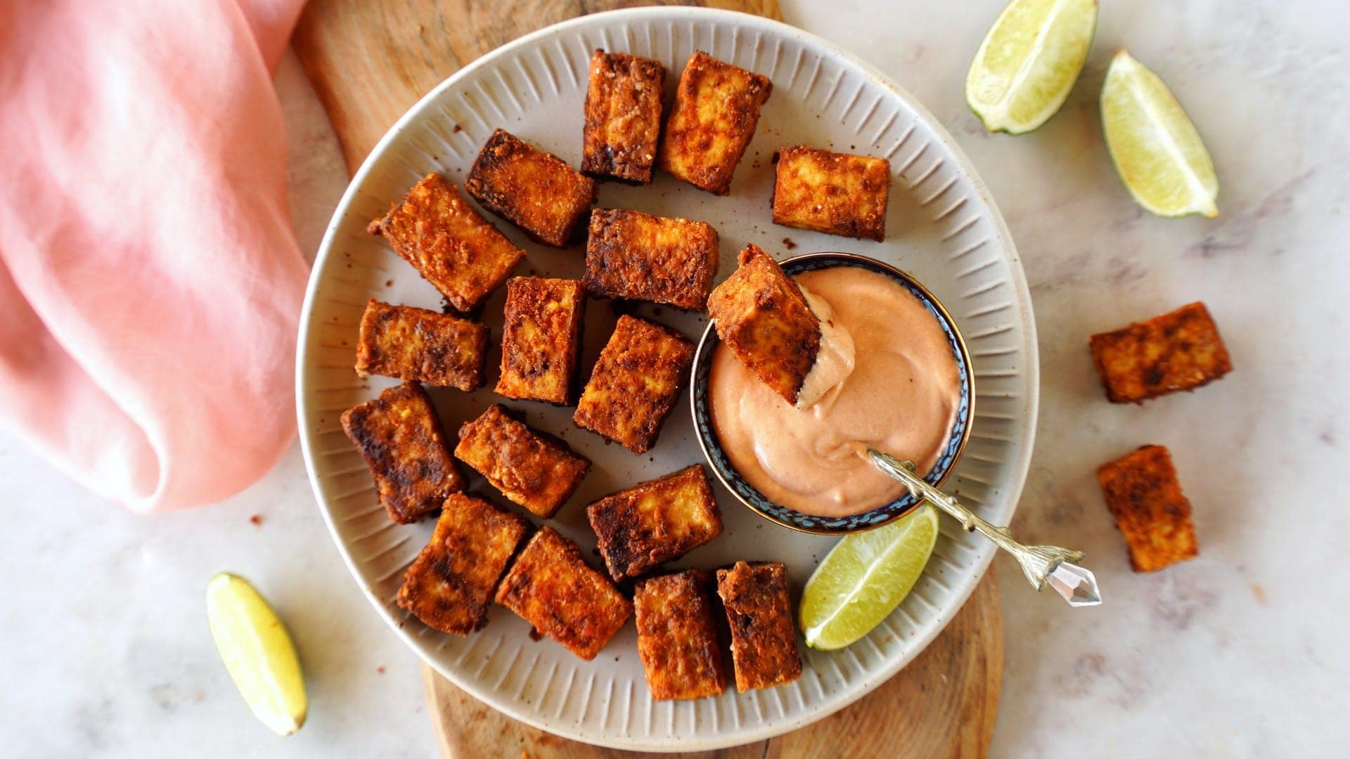 horizontal shot air fryer tofu on white plate with creamy dip and lime slices