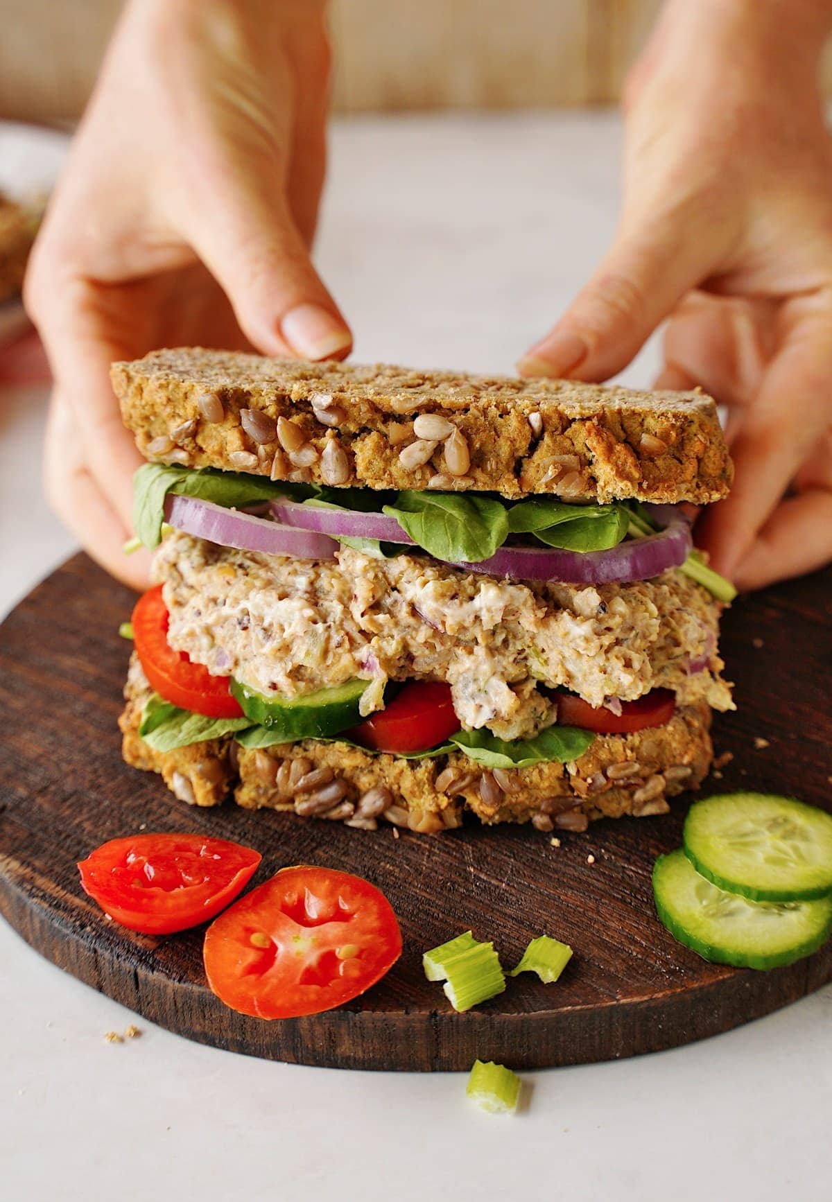 Hände greifen veganes Kichererbsen-Thunfisch-Salat-Sandwich
