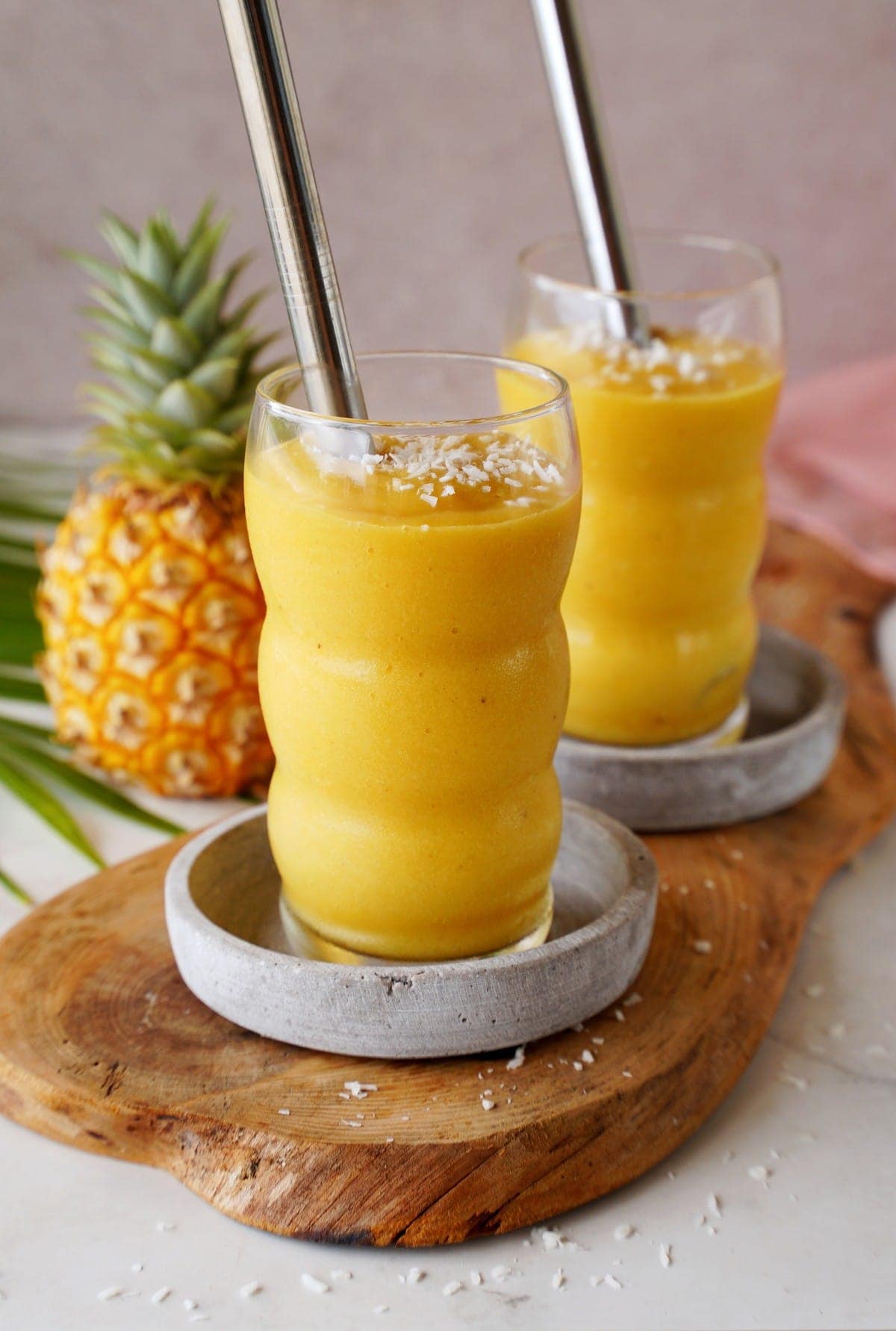 mango pineapple smoothie in 2 glasses with straws