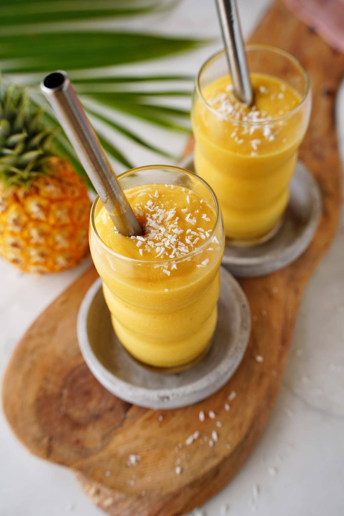 top shot of pineapple mango smoothie in two glasses with straws