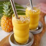 tropical mango pineapple smoothie in 2 glasses with straws