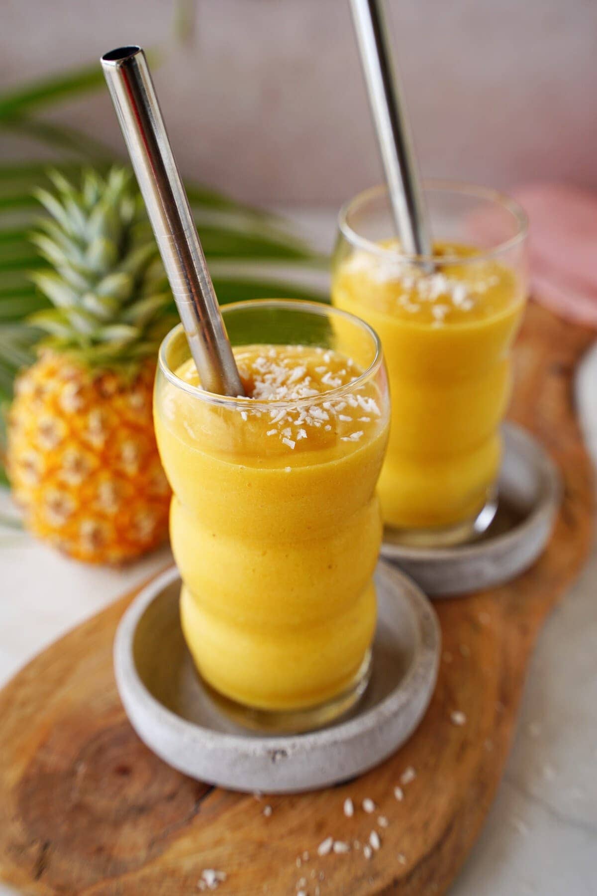 tropical mango pineapple smoothie in 2 glasses with straws