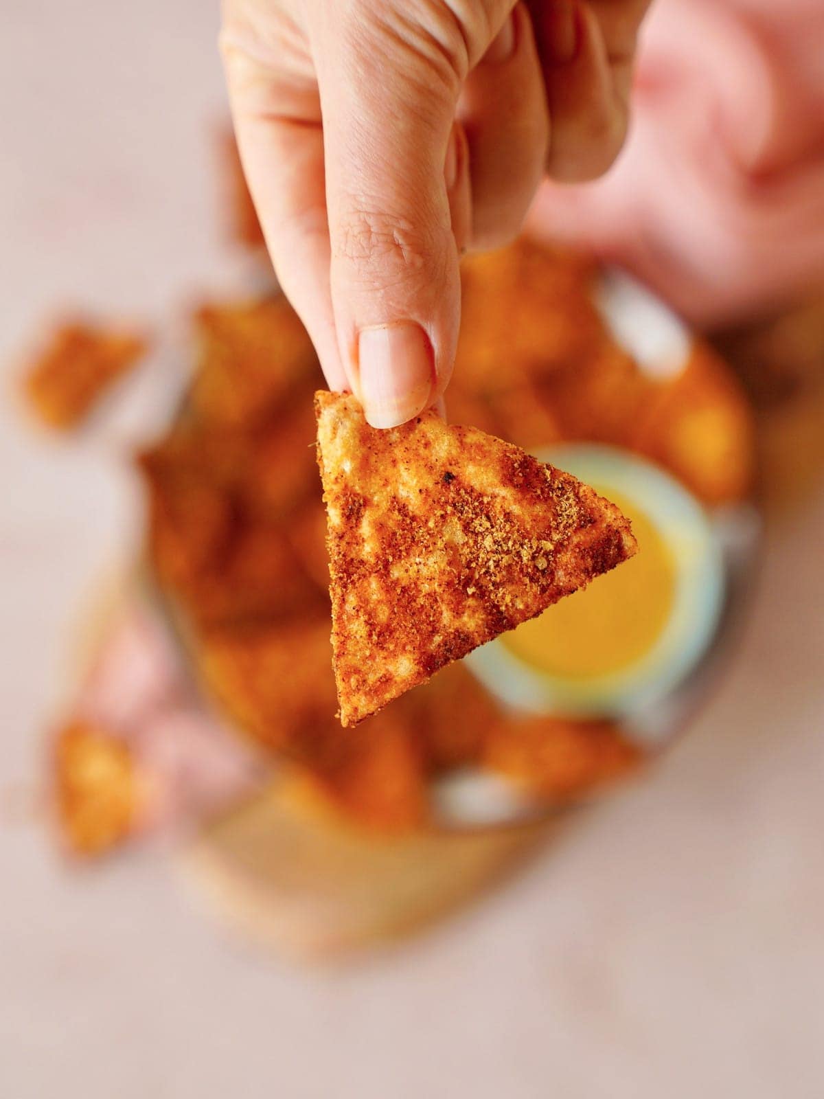 Hand hält einen knusprigen Tortilla-Chip