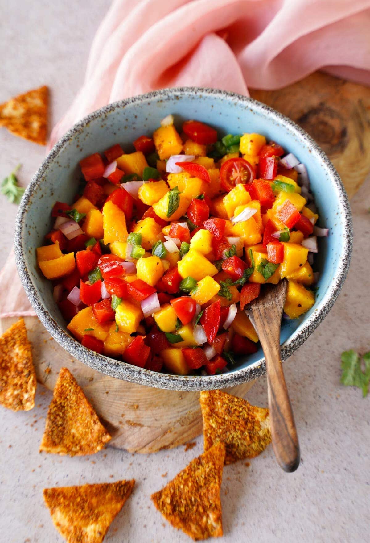 pico de gallo in bowl with wooden spoon and tortilla chips on the side