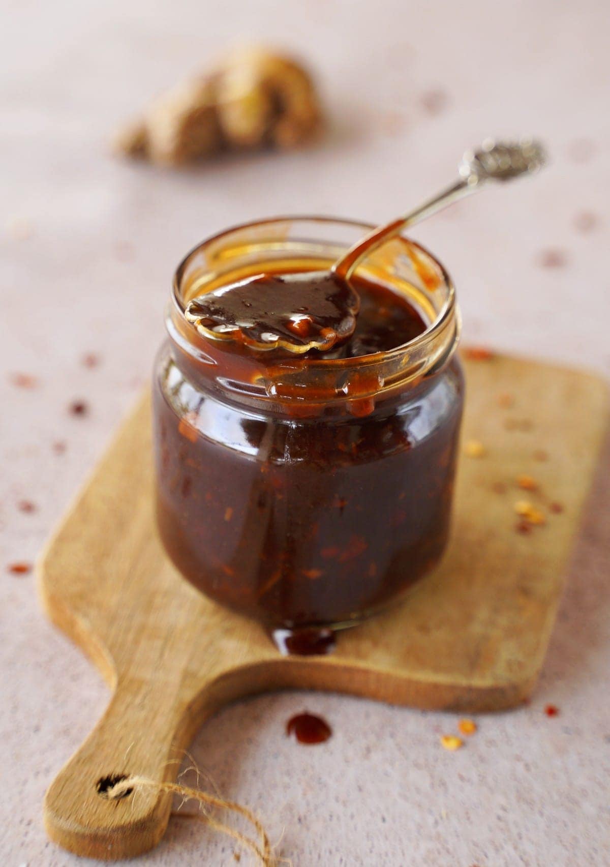 Asiatische Sauce süß sauer im Glas mit Löffel auf Holzbrett
