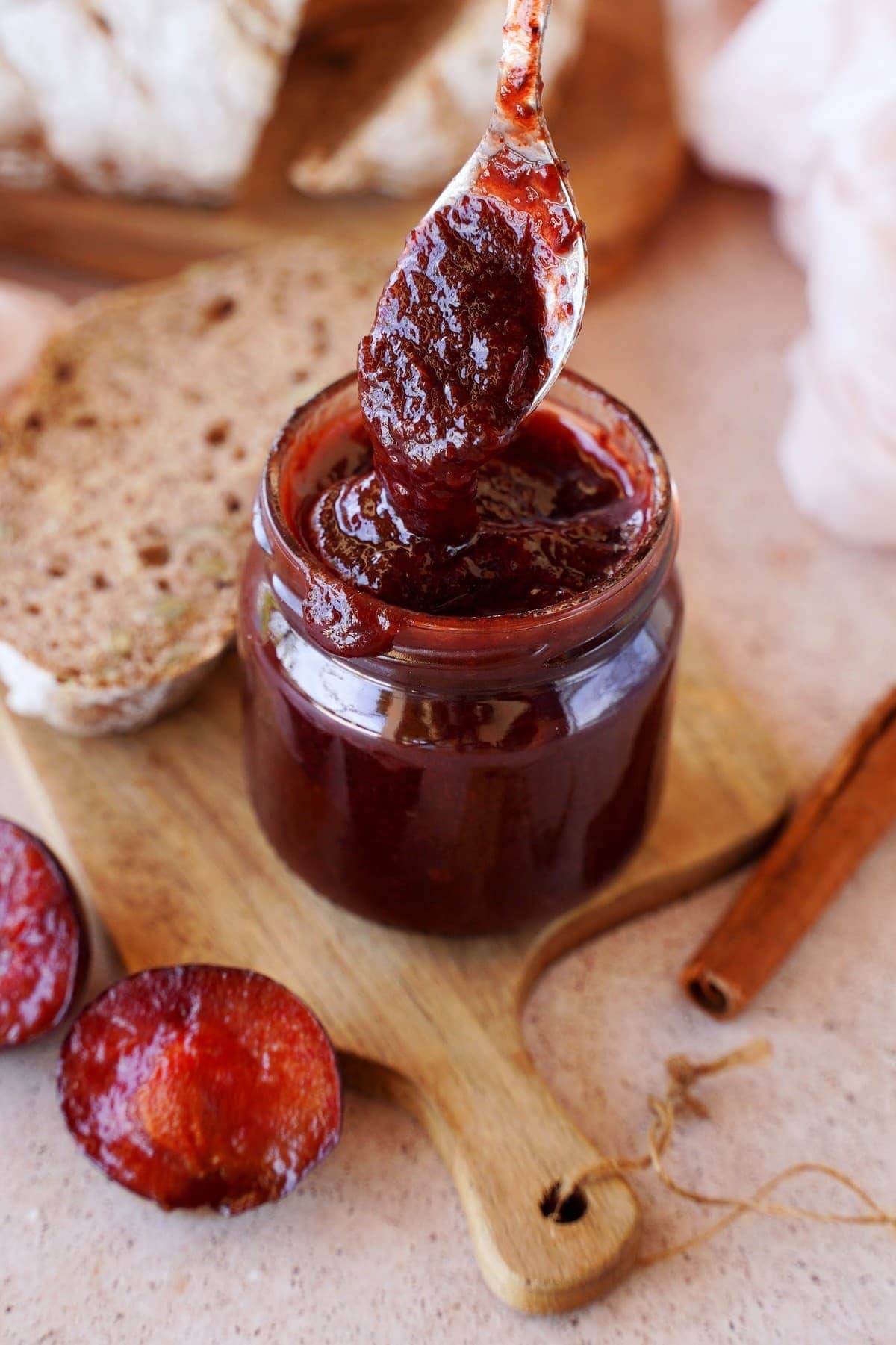 drizzling plum jam from spoon into jar