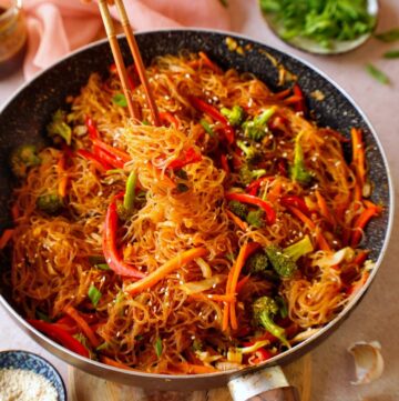 eating Asian vermicelli stir-fry with chopsticks from skillet