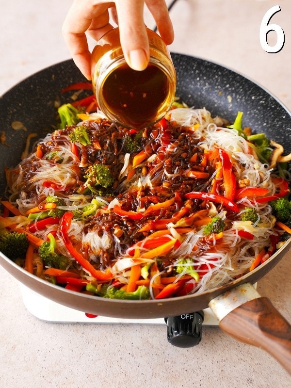 pouring Korean BBQ sauce over Asian stir-fry