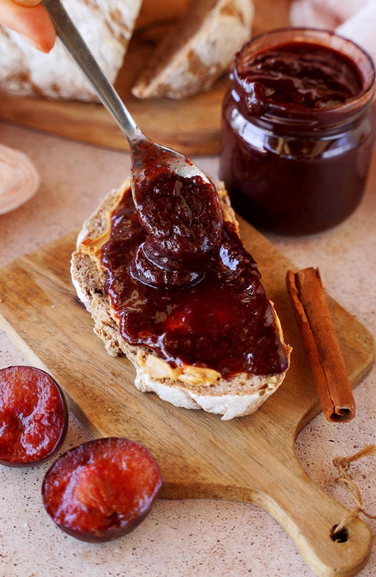 putting plum jam on bread with spoon