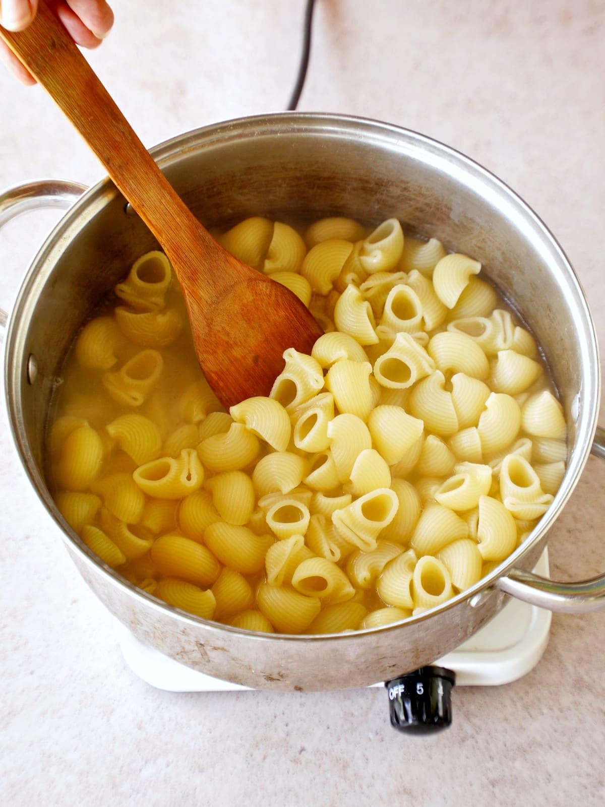 Cooking pasta in pot with wooden spoon