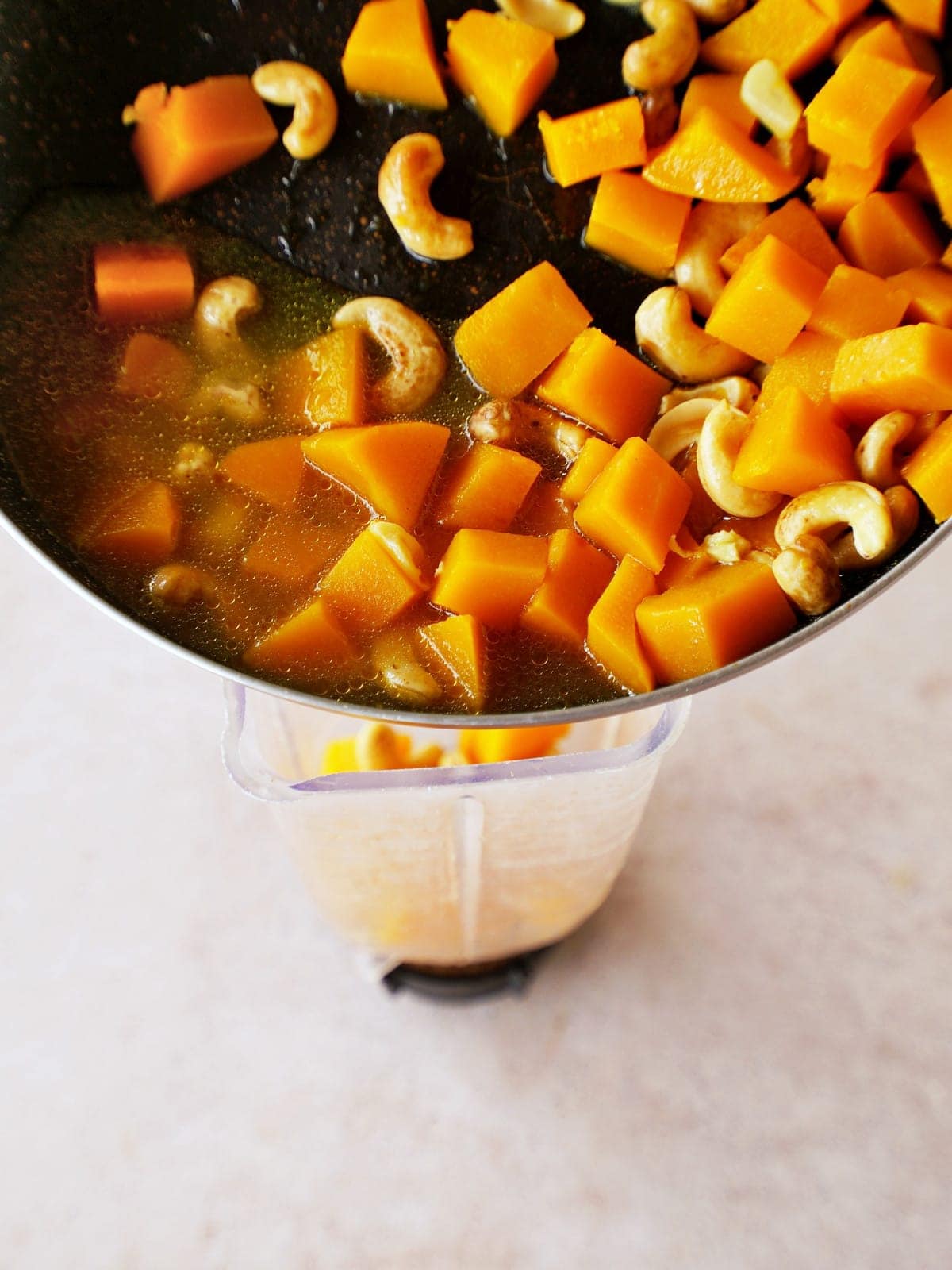 adding cooked squash and cashews to blender
