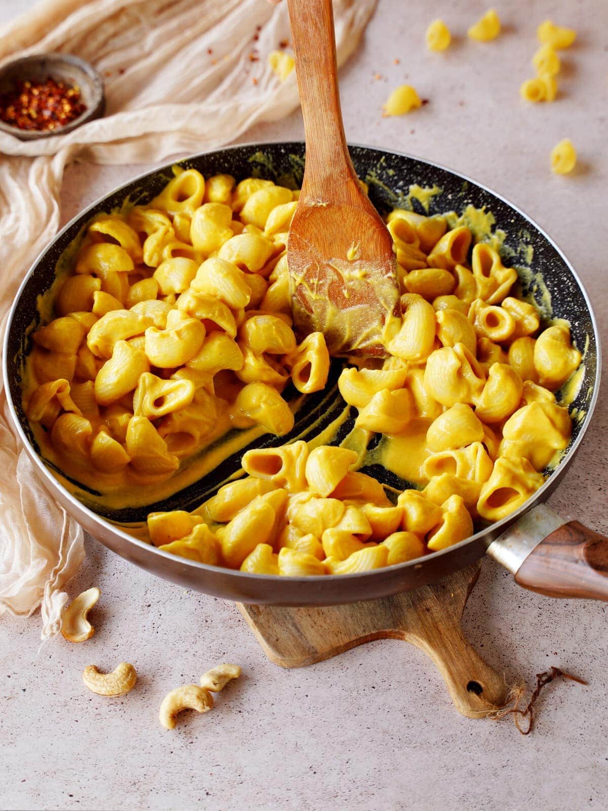 dairy free butternut mac and cheese in black skillet with wooden spoon