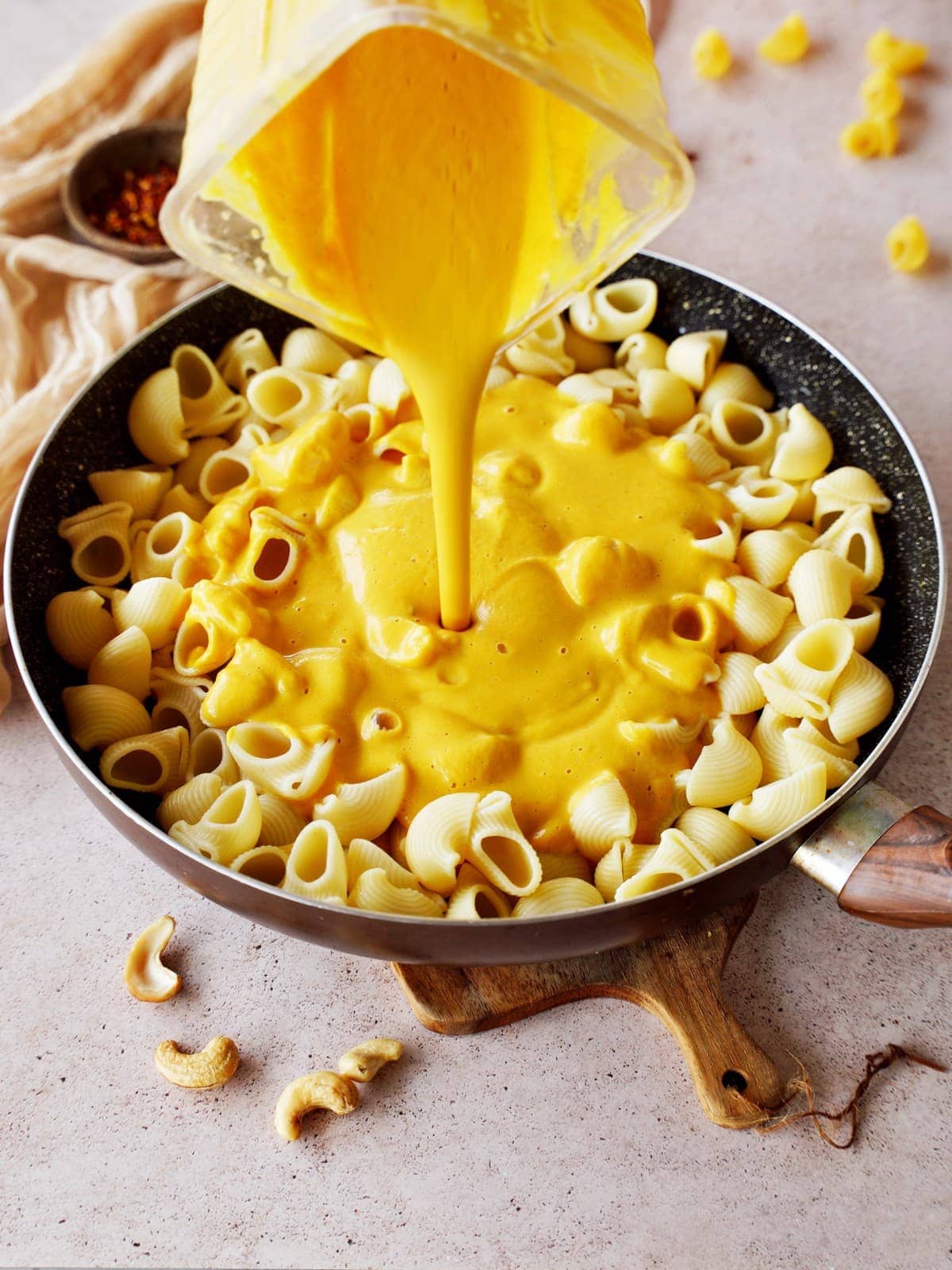pouring vegan butternut mac and cheese into black skillet