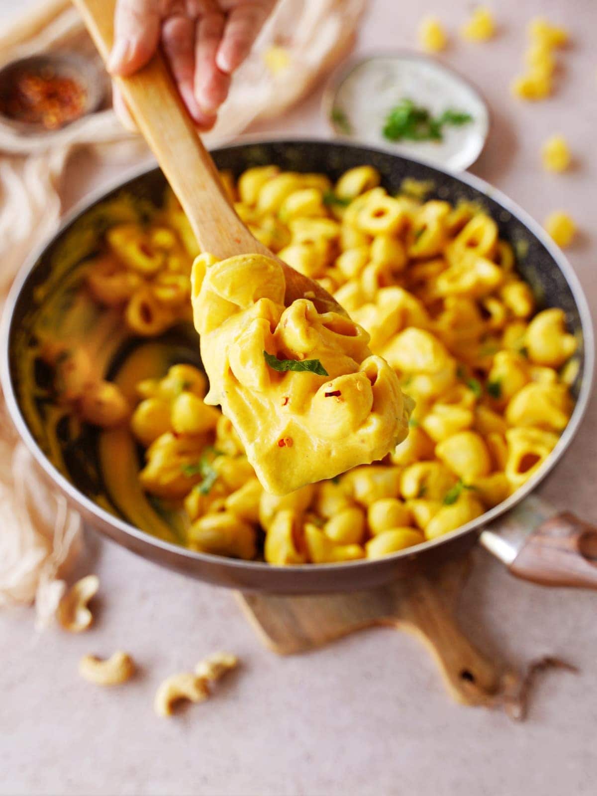 vegan butternut mac and cheese in black skillet with wooden spoon
