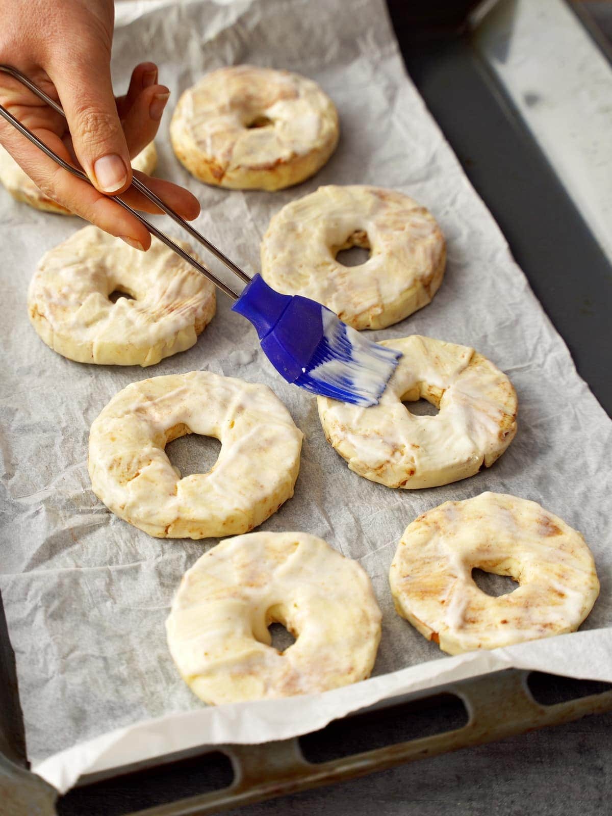brushing wrapped puff pastry apple rings with coconut milk