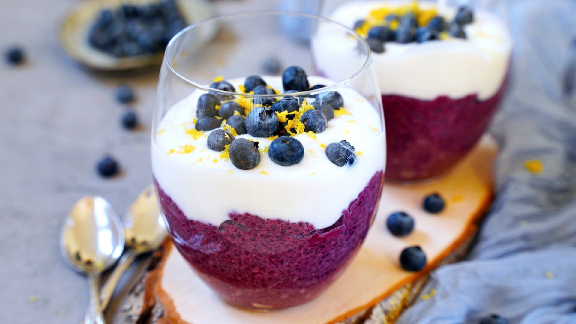 horizontal shot blueberry chia seed pudding in two jars with yogurt and fresh berries