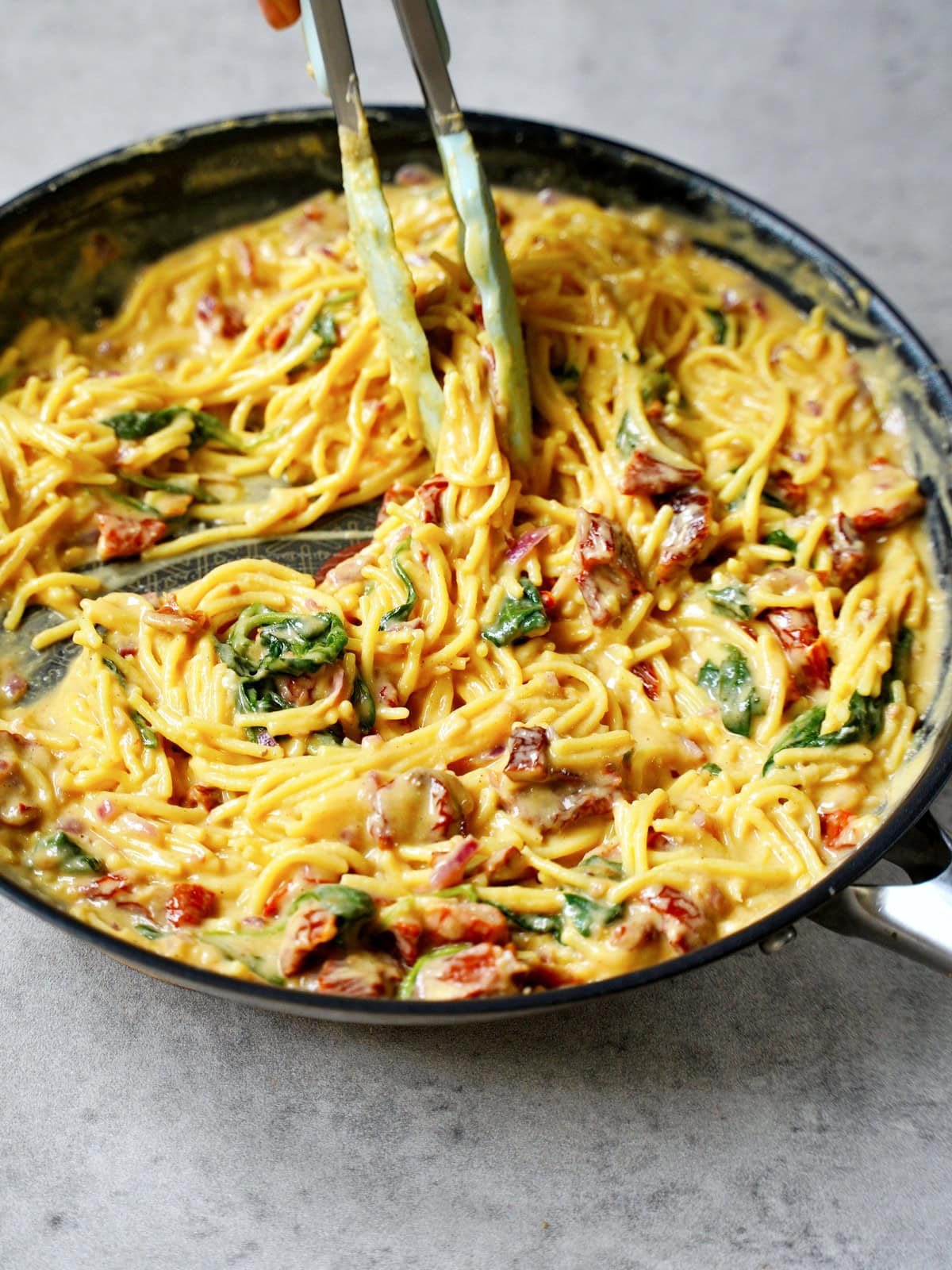 creamy spaghetti with hummus sauce and sun-dried tomatoes in skillet