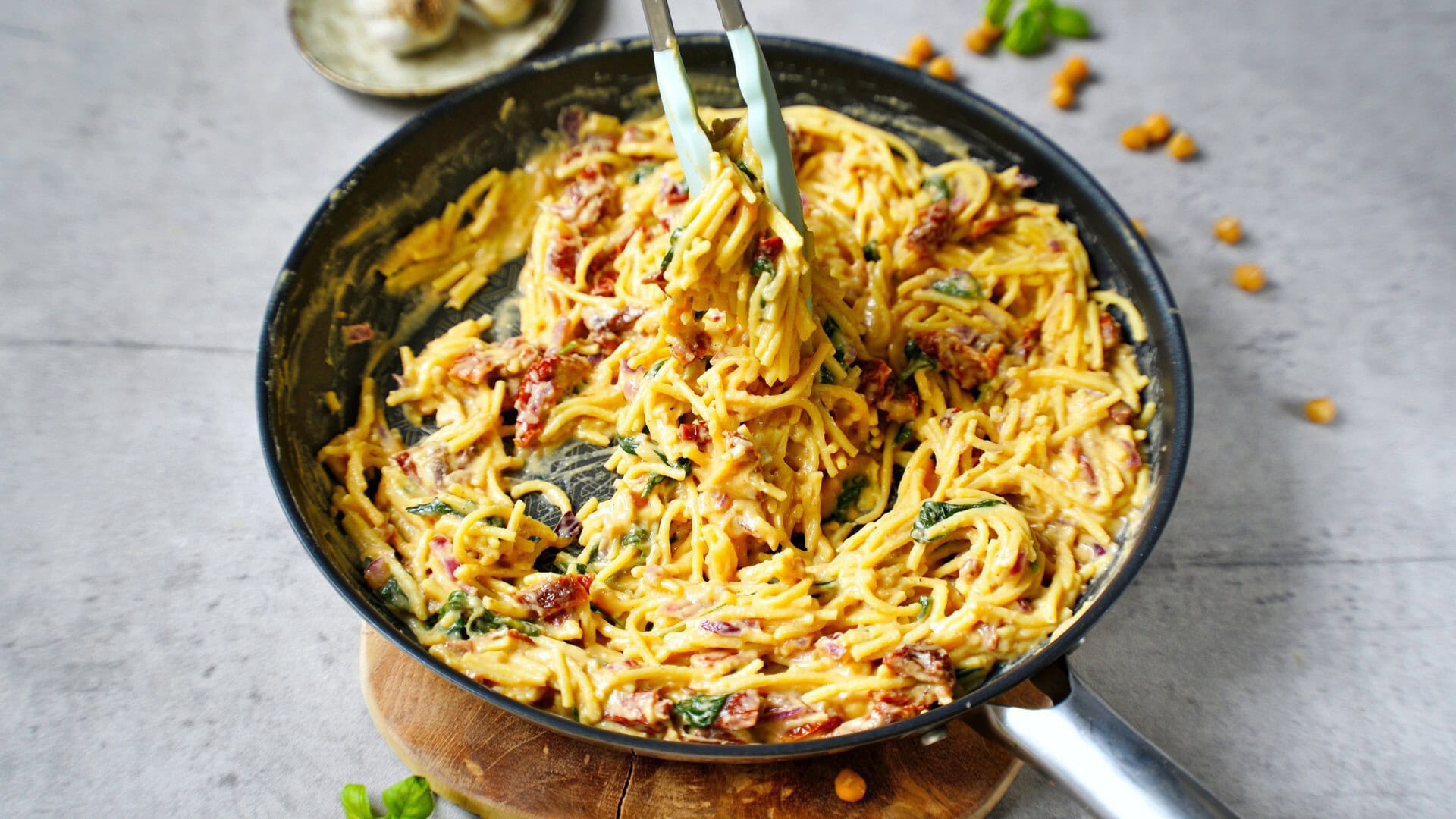 horizontal image of hummus pasta with sun-dried tomatoes in skillet