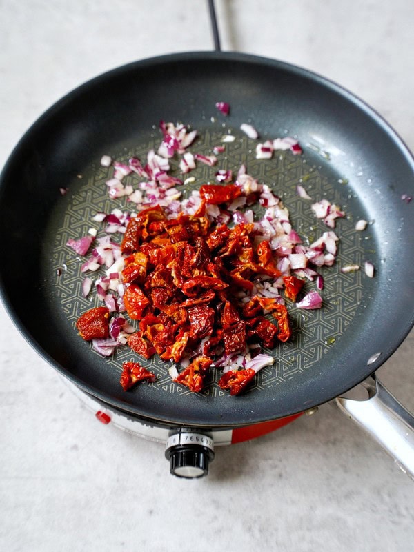 onion and sun-dried tomatoes in skillet