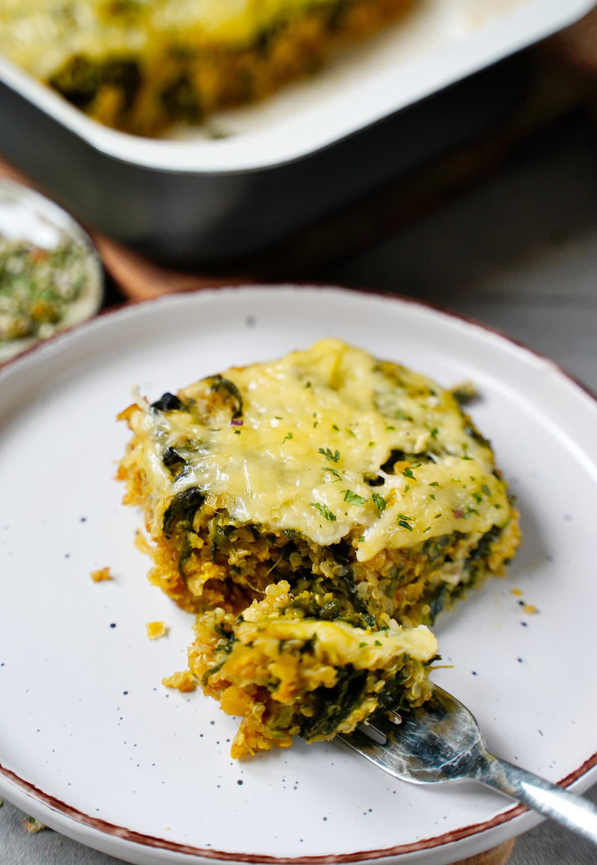 piece of spinach casserole with cheese on plate and fork