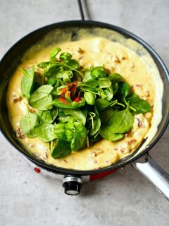 spinach and basil in creamy sauce in skillet