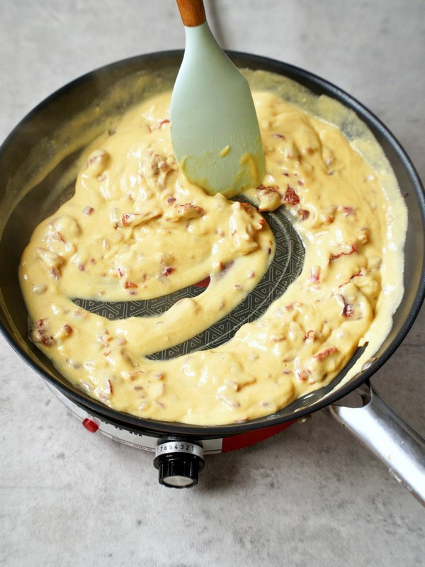 stirring creamy sauce in skillet with spatula