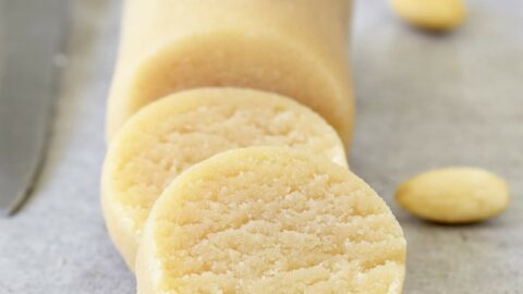 sliced log of homemade marzipan with blanched almonds on the side
