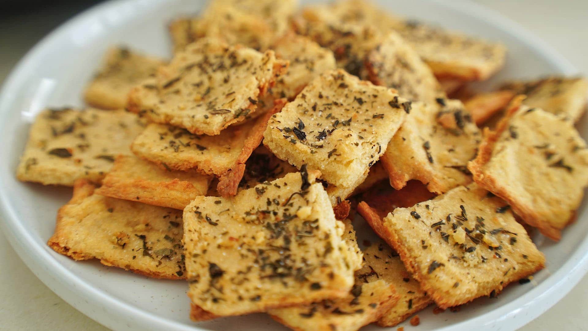 Crispy chickpea crackers with herbs on white plate