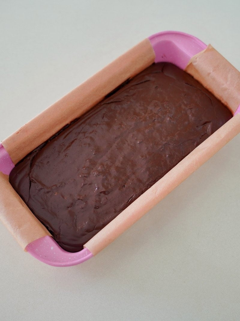Chocolate batter in a pink loaf pan lined with parchment paper