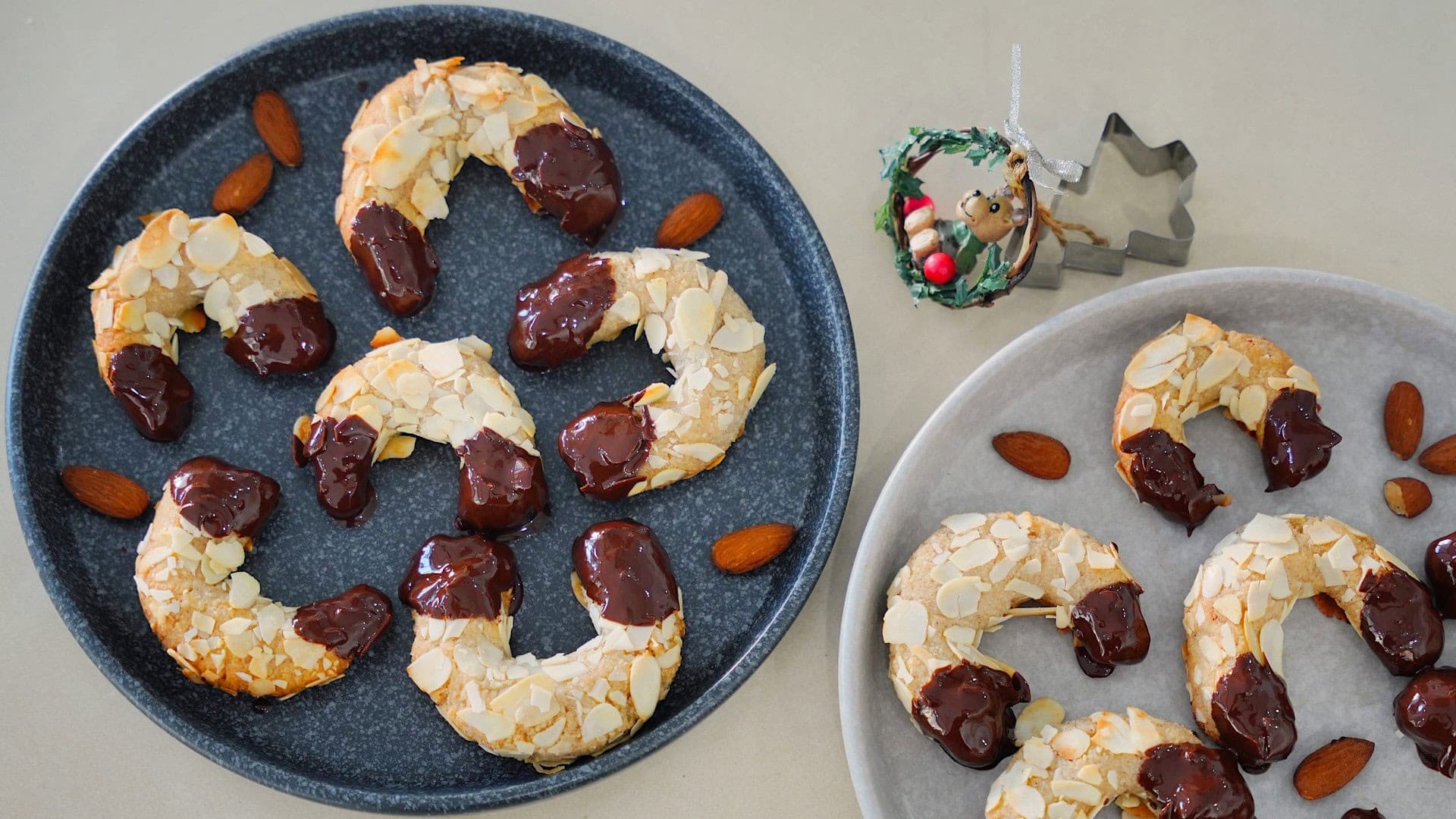 Teller mit veganen Mandelhörnchen, dekoriert mit ganzen Mandeln.