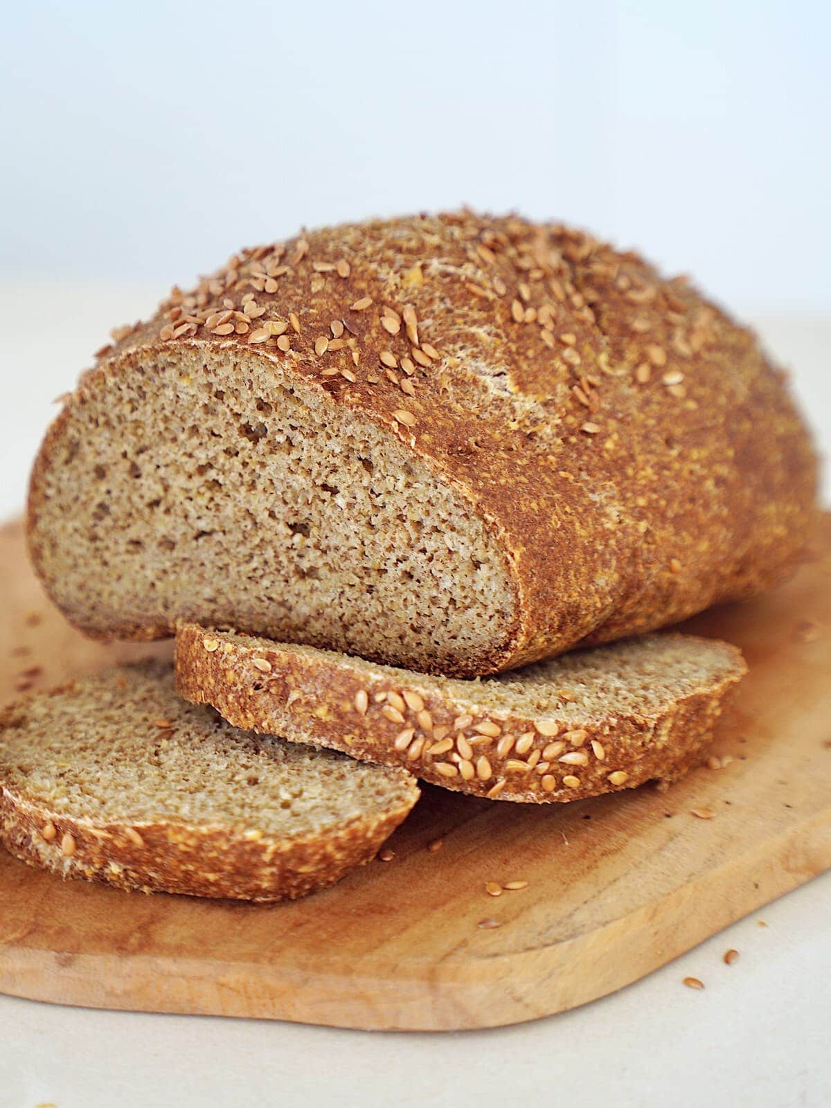 A loaf of homemade chickpea bread on a wooden board, with two slices cut
