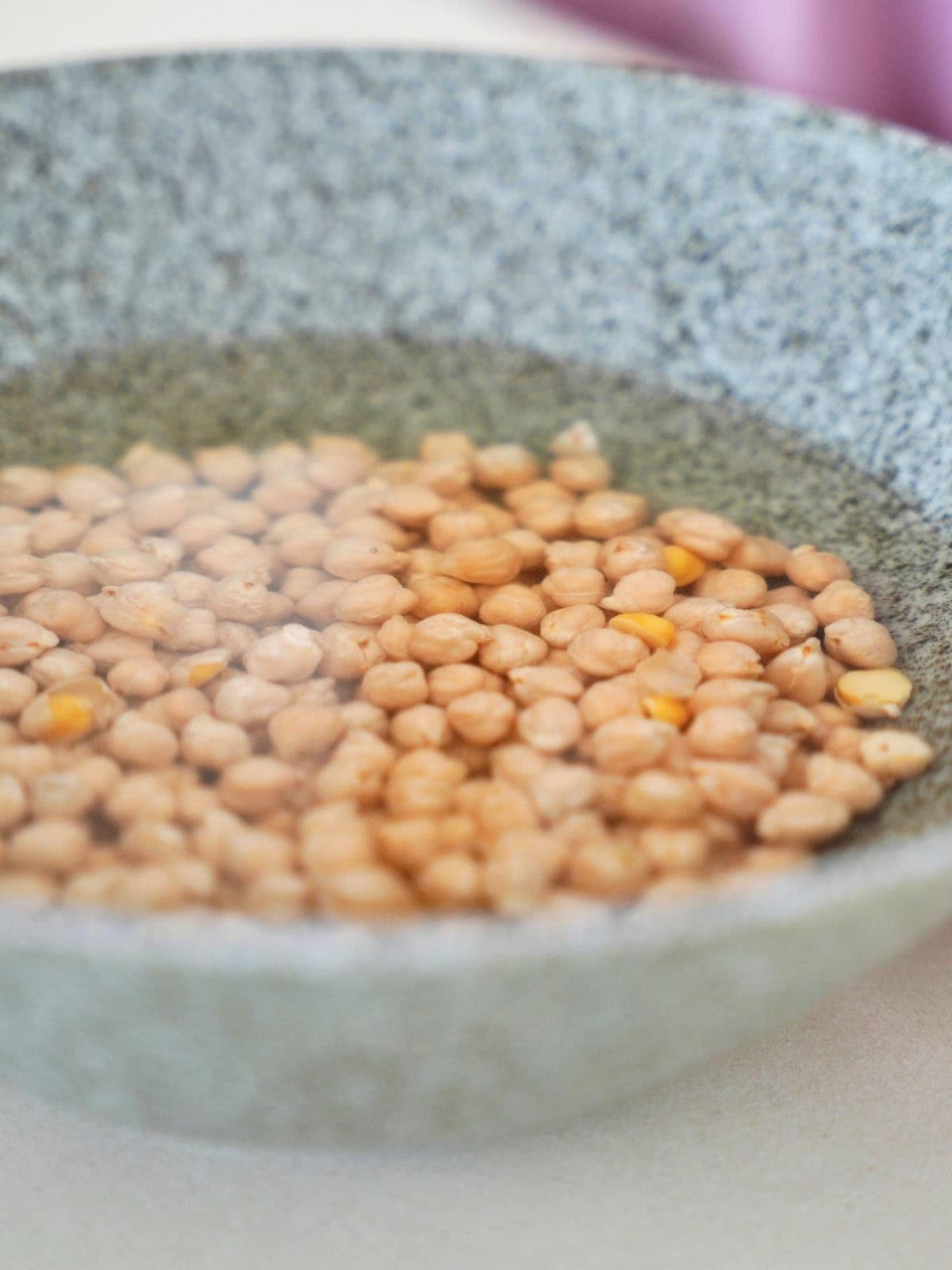 Chickpeas soaking in a gray bowl filled with water