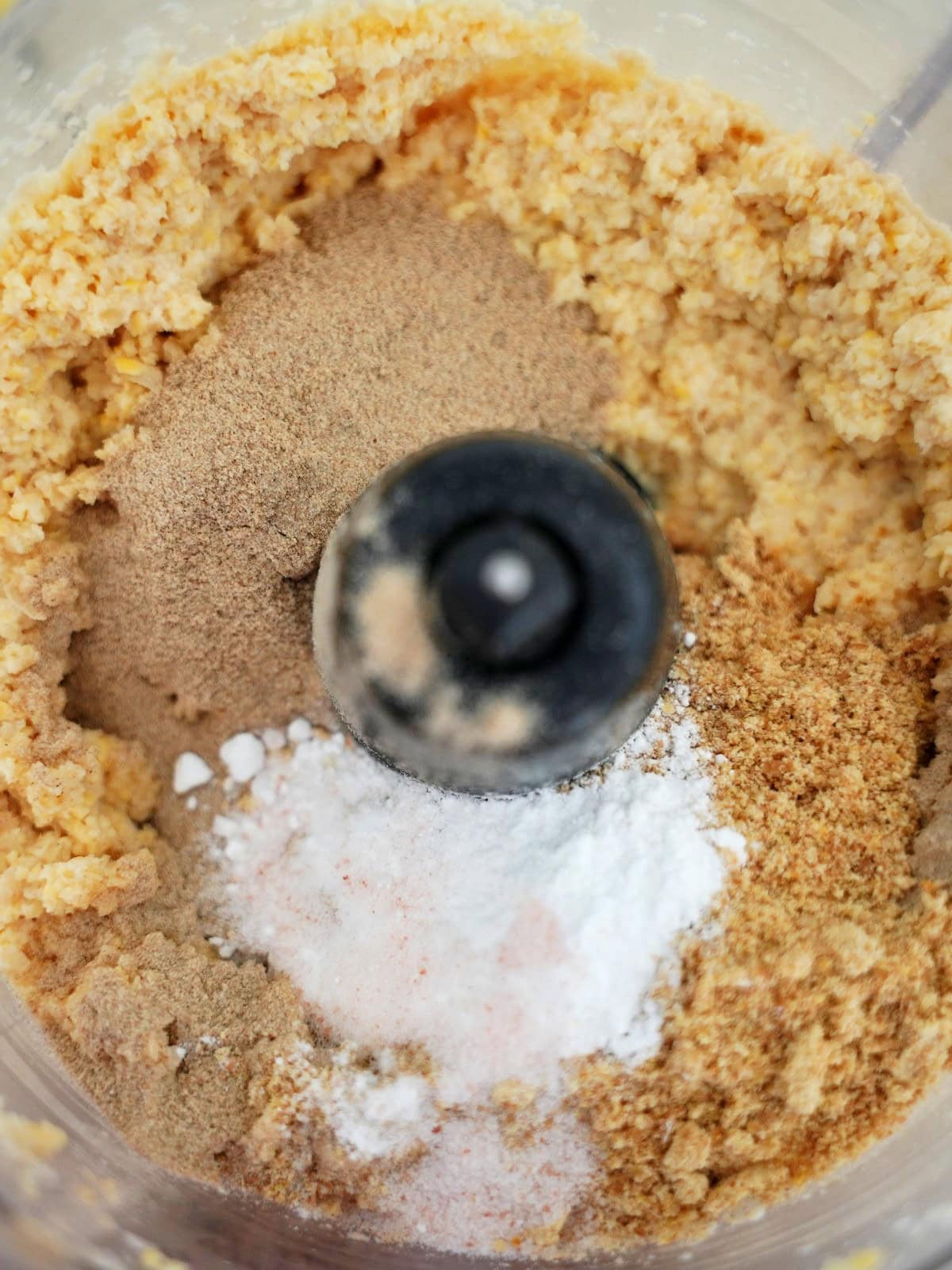 Close-up of a food processor bowl containing mixed dry ingredients